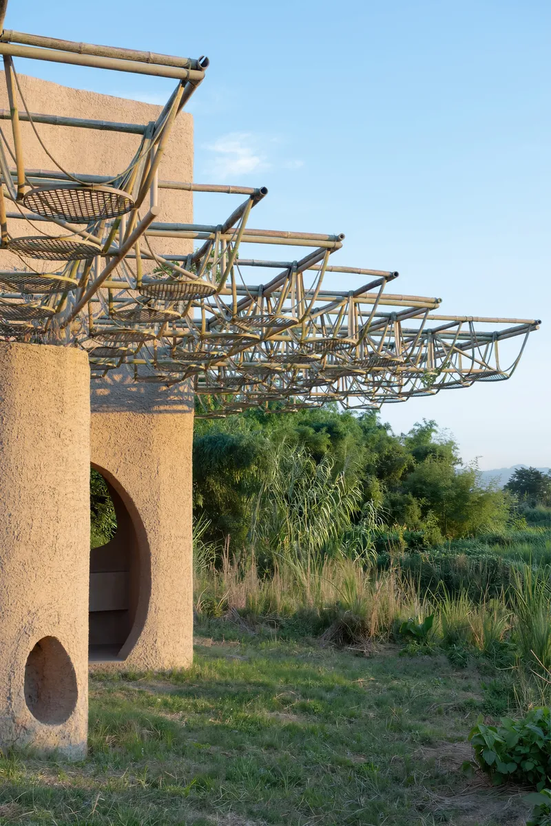 Detail of the bamboo frame canopy structure extending from cylindrical earthen columns with arched voids