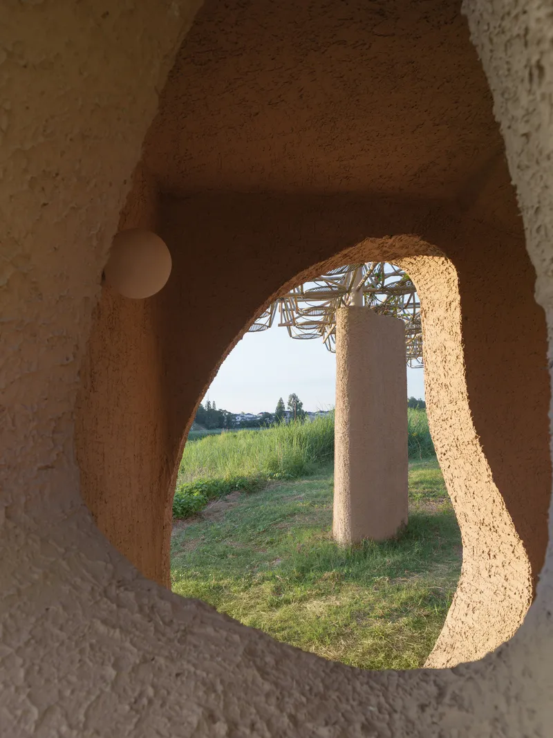 View through an organic arched opening framing the bamboo canopy and distant landscape at dusk