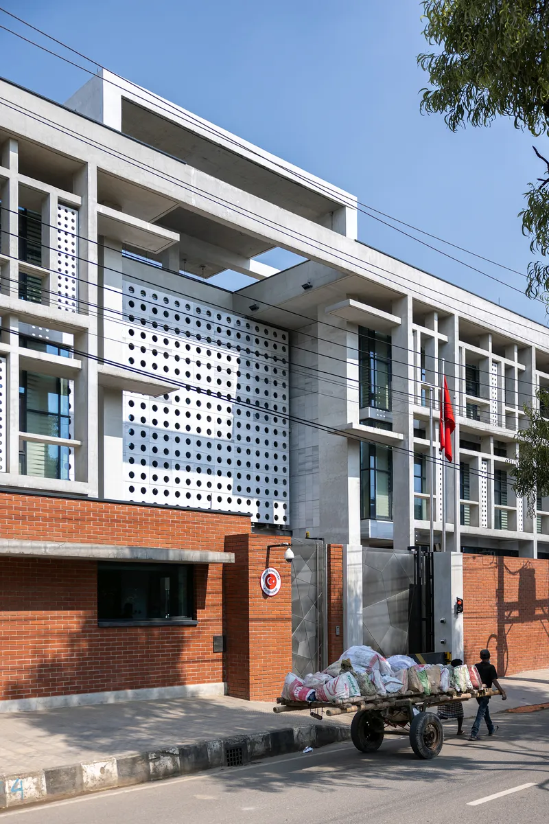 Front facade with perforated white panels and recessed entrance as a cart passes on the street