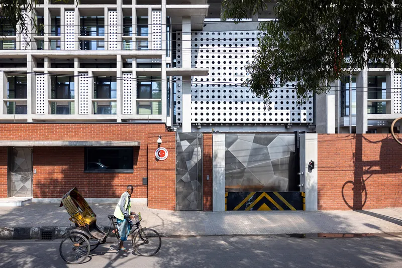 Street view of the brick and perforated metal facade with a cyclist passing by