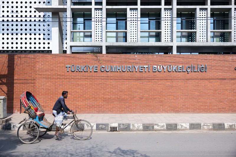 Red brick wall with raised metal lettering below the perforated facade and concrete structure