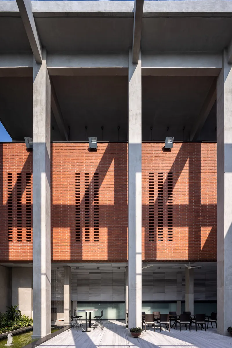 Perforated brick screen wall behind concrete columns casting sharp shadows in bright sunlight