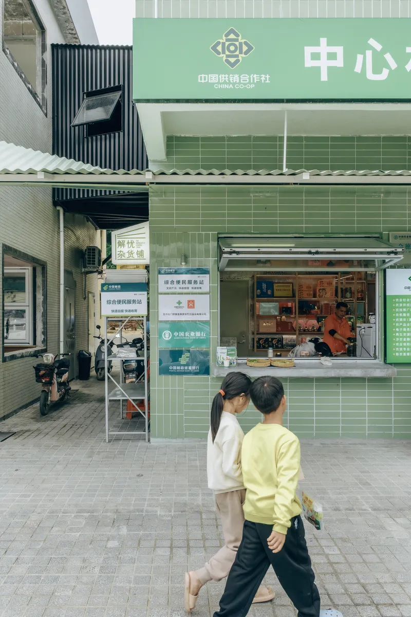 Street view of the mint green tiled kiosk with two pedestrians passing in front