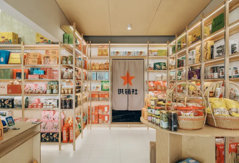Interior retail space with timber shelving displaying packaged goods and a curtained doorway with red star