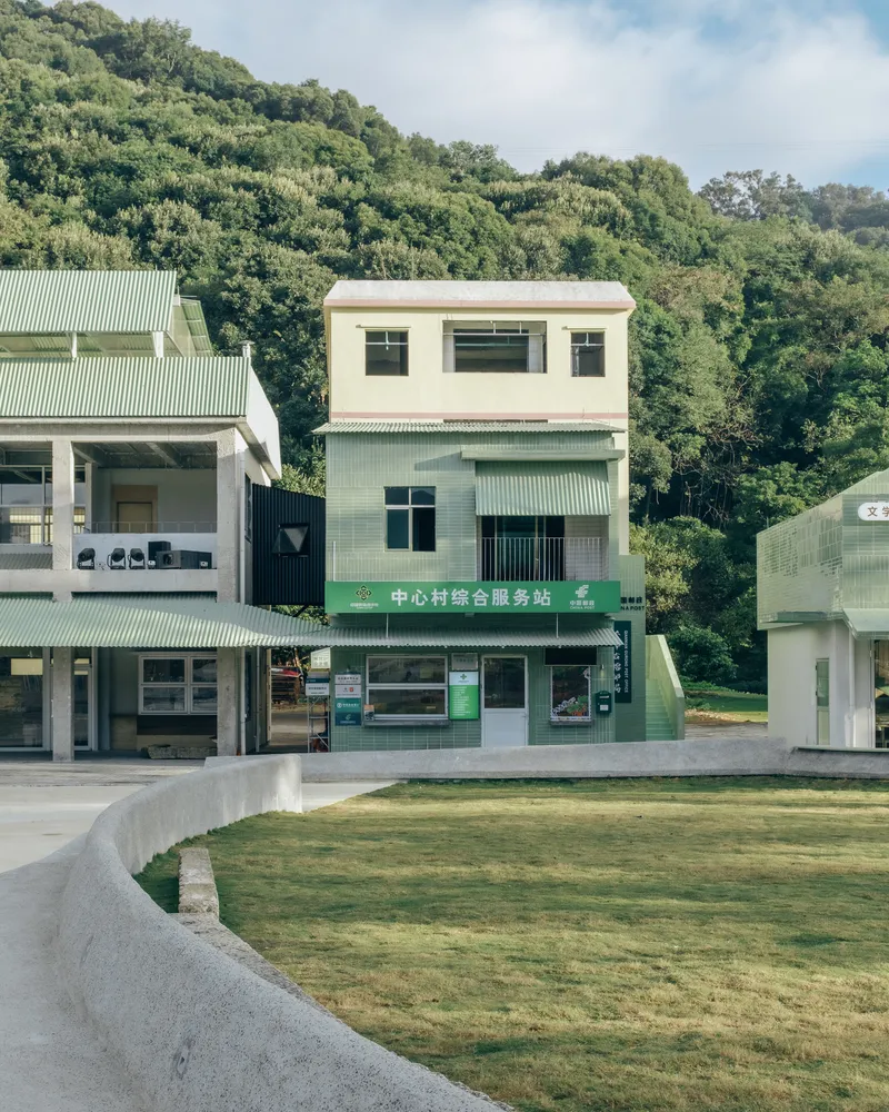 Three-story volume clad in mint-green corrugated metal and white stucco beside a curved concrete lawn edge