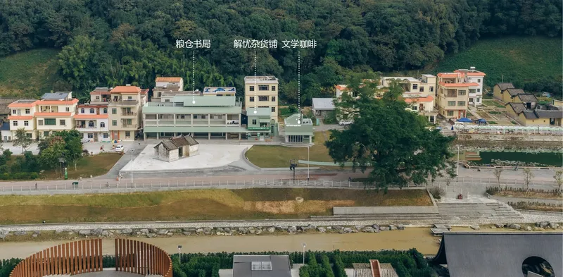 Elevated view showing the terraced plaza with preserved heritage pavilion and long green-roofed community building behind