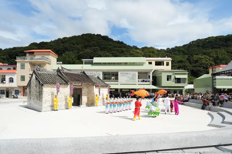 Ceremonial gathering in the plaza around the restored stone pavilion with performers in traditional dress