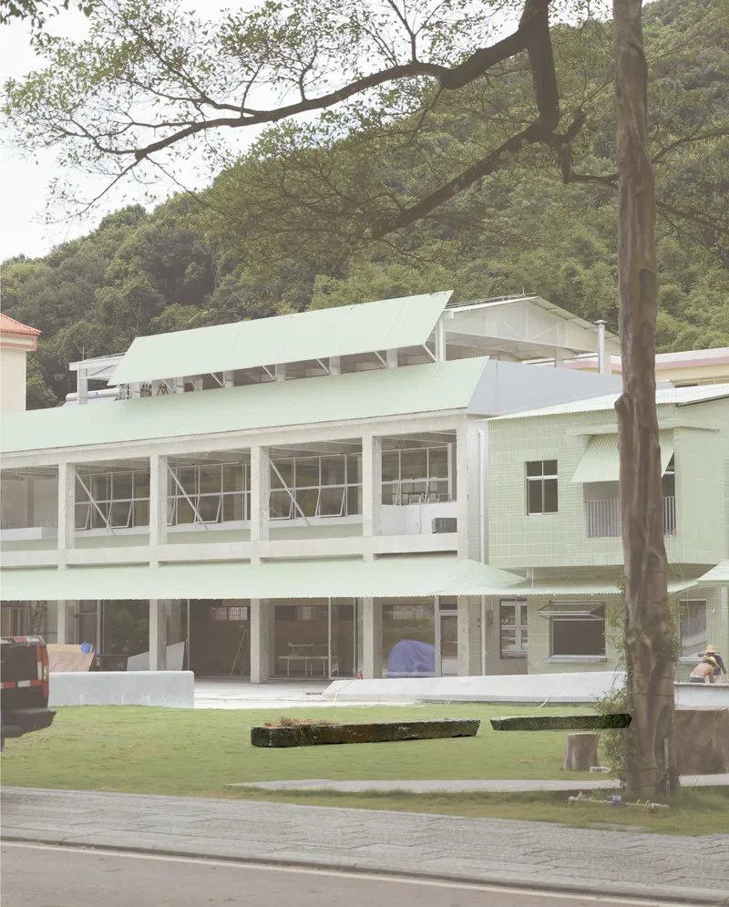 Two-story facade with exposed concrete columns and continuous ribbon windows facing a grass lawn with tree