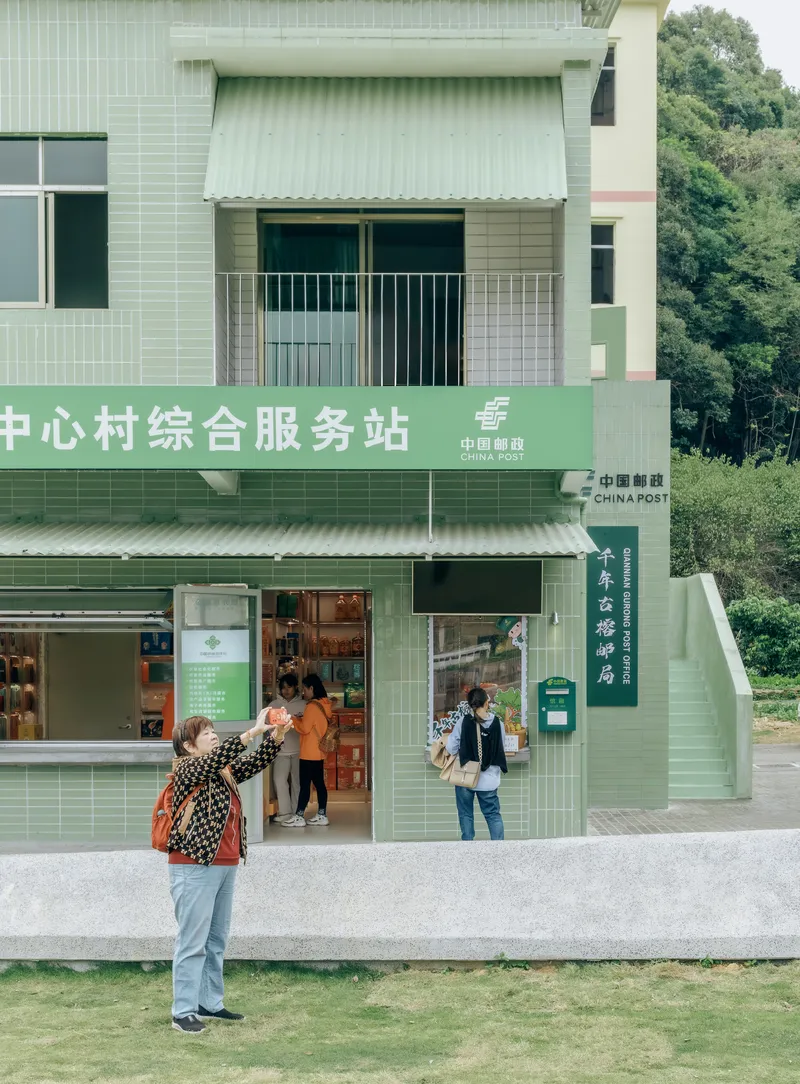 Green-clad storefront with canopy and signage as visitors gather at the entrance