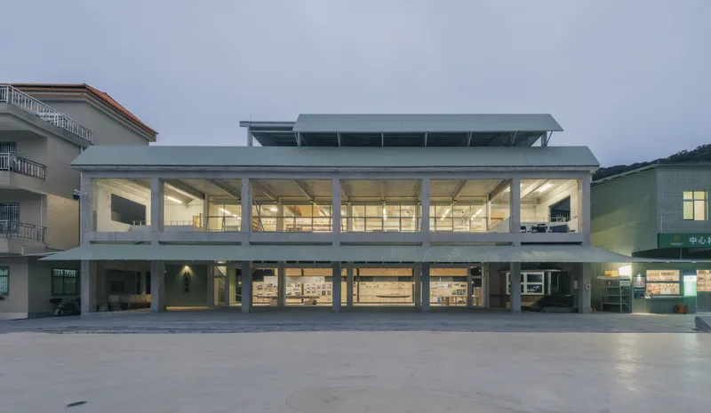 Front elevation showing the open ground floor colonnade and upper glazed volume beneath a metal canopy roof