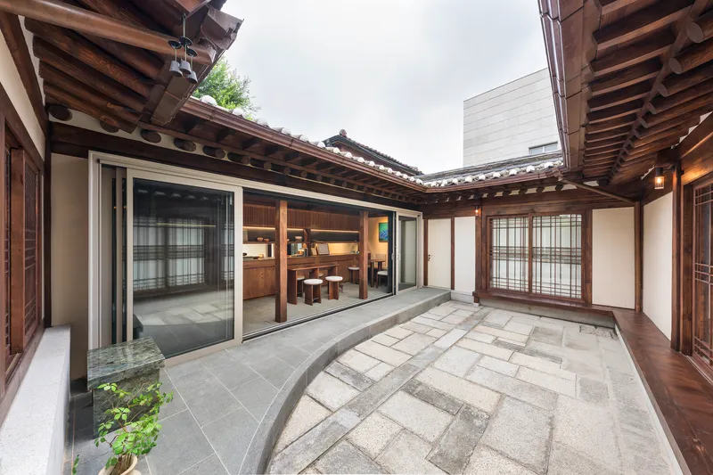 Courtyard with stone paving and planted bed surrounded by traditional timber-framed buildings under overcast sky