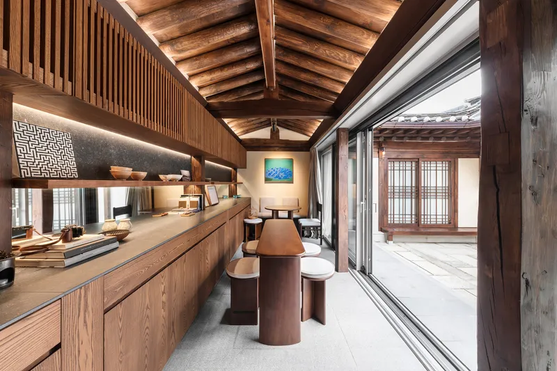 Interior kitchen with exposed timber rafters, vertical wood slat partitions and backlit countertop alcove
