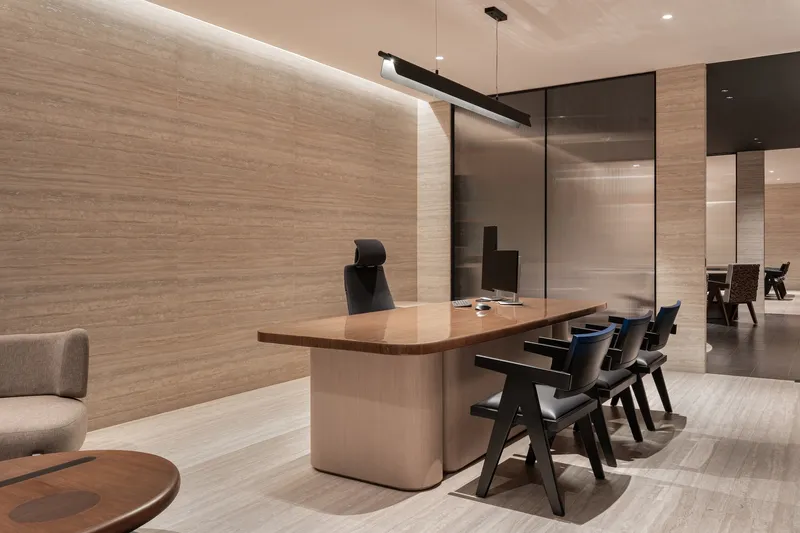 Meeting area with timber table, black chairs, and textured wood wall with concealed linear lighting
