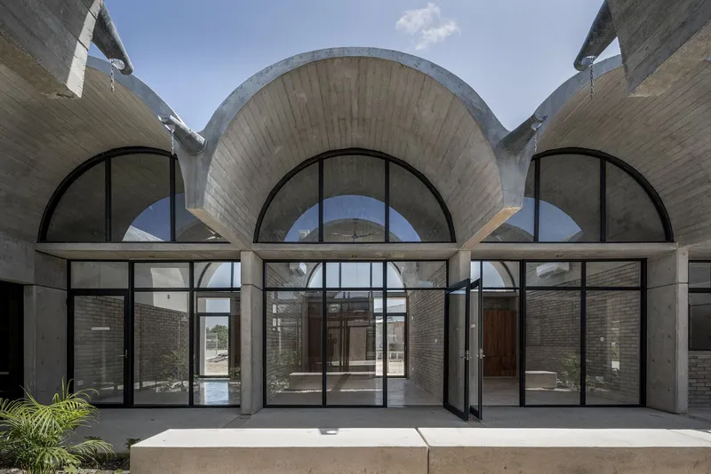 Symmetrical facade showing three arched openings with concrete horizontal beam under vaulted shells