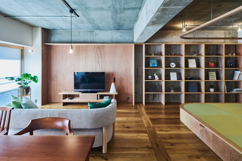 Living area with timber shelving wall, raised tatami platform, and potted plant by the window