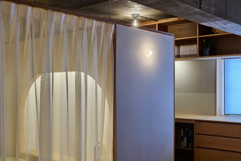 Curved translucent curtain in front of an arched opening with light filtering through at dusk
