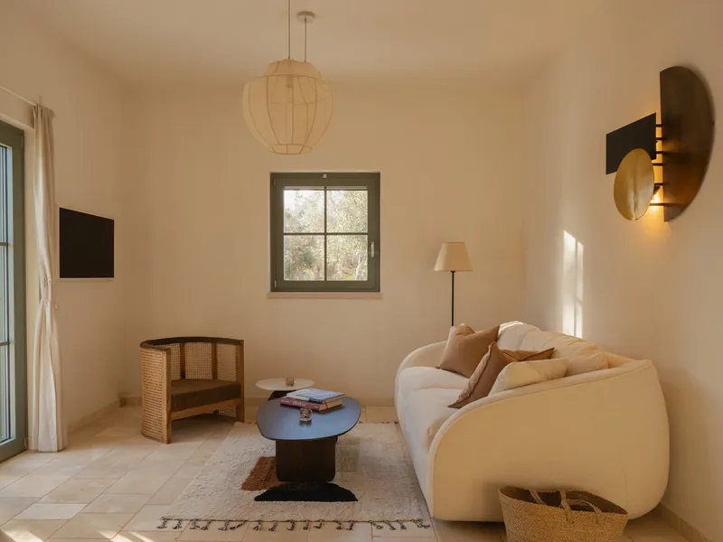 Sitting area with globe pendant and small framed window allowing sunlight onto pale stone flooring