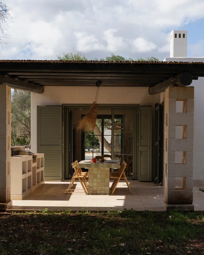 Covered terrace with timber beam roof and folding glass doors opening to an interior dining area