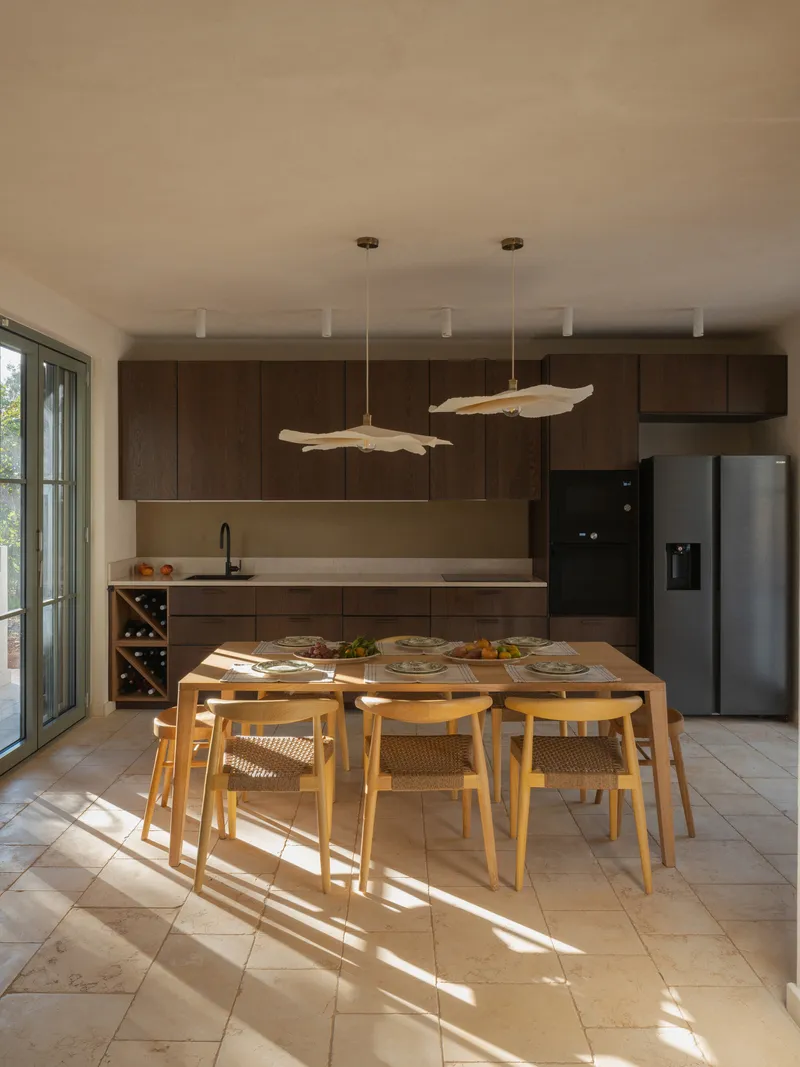 Dining area with dark timber cabinetry and driftwood pendant lights above a timber table