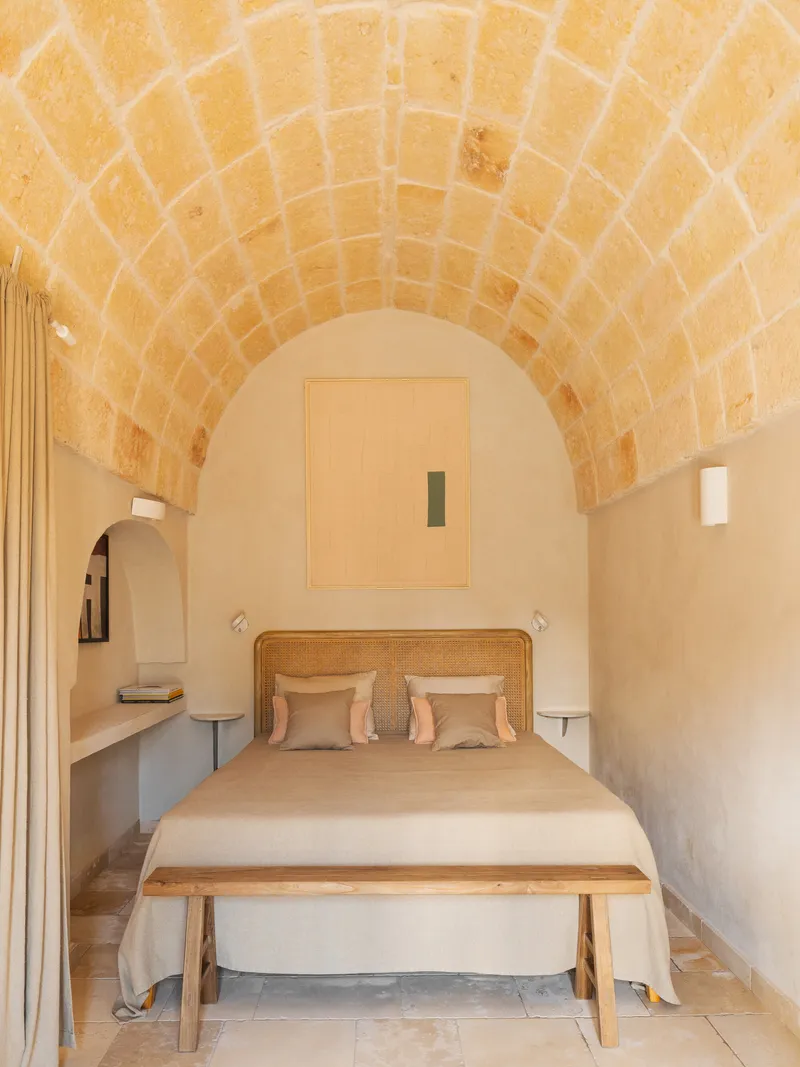 Bedroom with barrel-vaulted stone ceiling and built-in shelving flanking a cane headboard