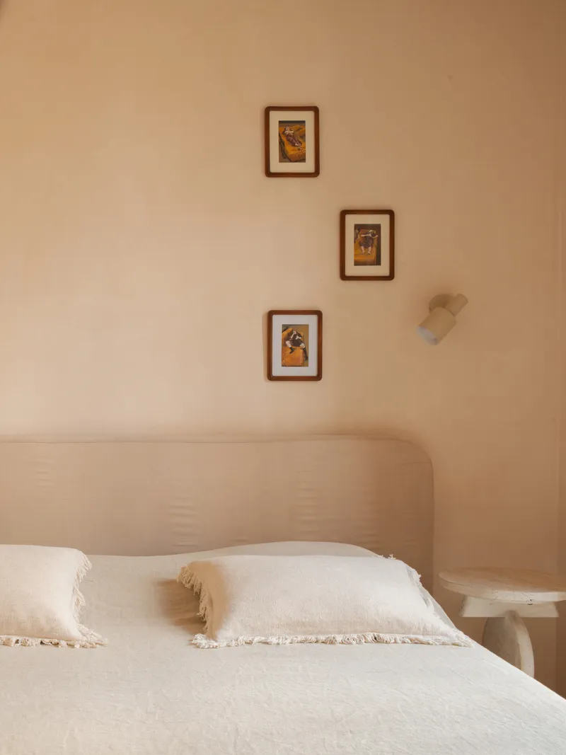 Corner of bedroom showing three framed artworks arranged diagonally above a bed