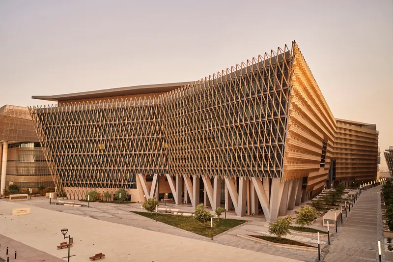 Corner view of the parametric timber lattice facade supported by angular concrete columns in afternoon light
