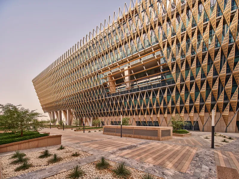Ground-level view of the lattice facade with carved aperture above the landscaped entrance plaza