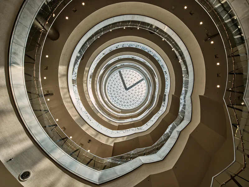 Looking up through the circular atrium well showing concentric rings of balconies to a geometric skylight