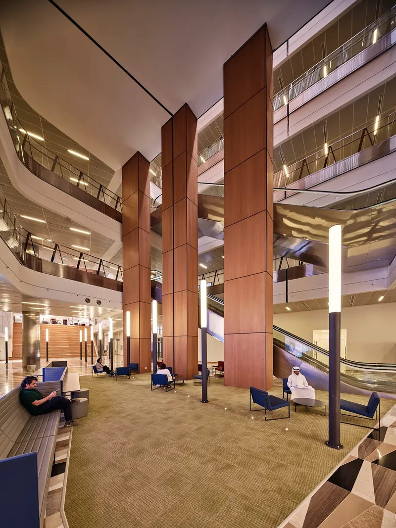Atrium lobby with tall timber-paneled columns and carpeted seating area at dusk