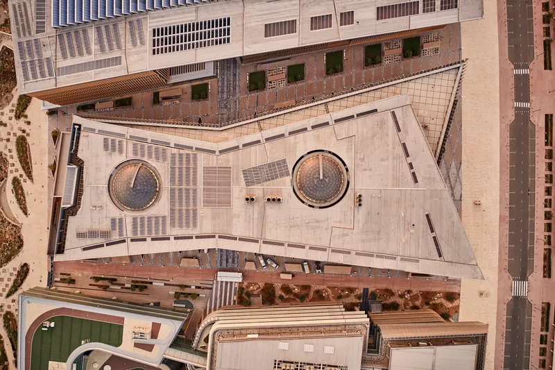 Aerial view of triangular concrete plaza with two circular planters and pedestrians below