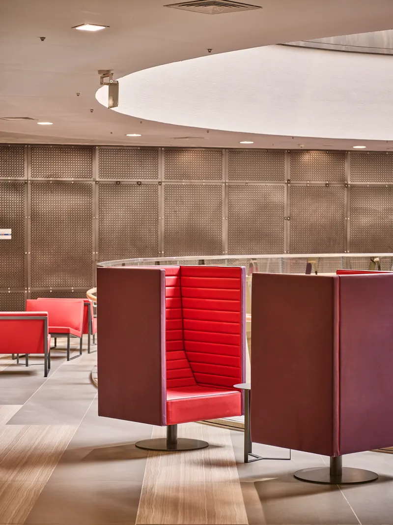 Red upholstered booth seating with privacy screens beneath a curved white ceiling soffit