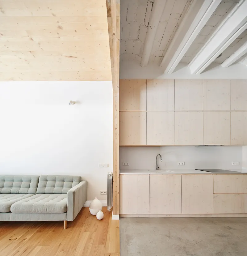 Open-plan kitchen and living area with plywood cabinetry, exposed timber beams and polished concrete floor