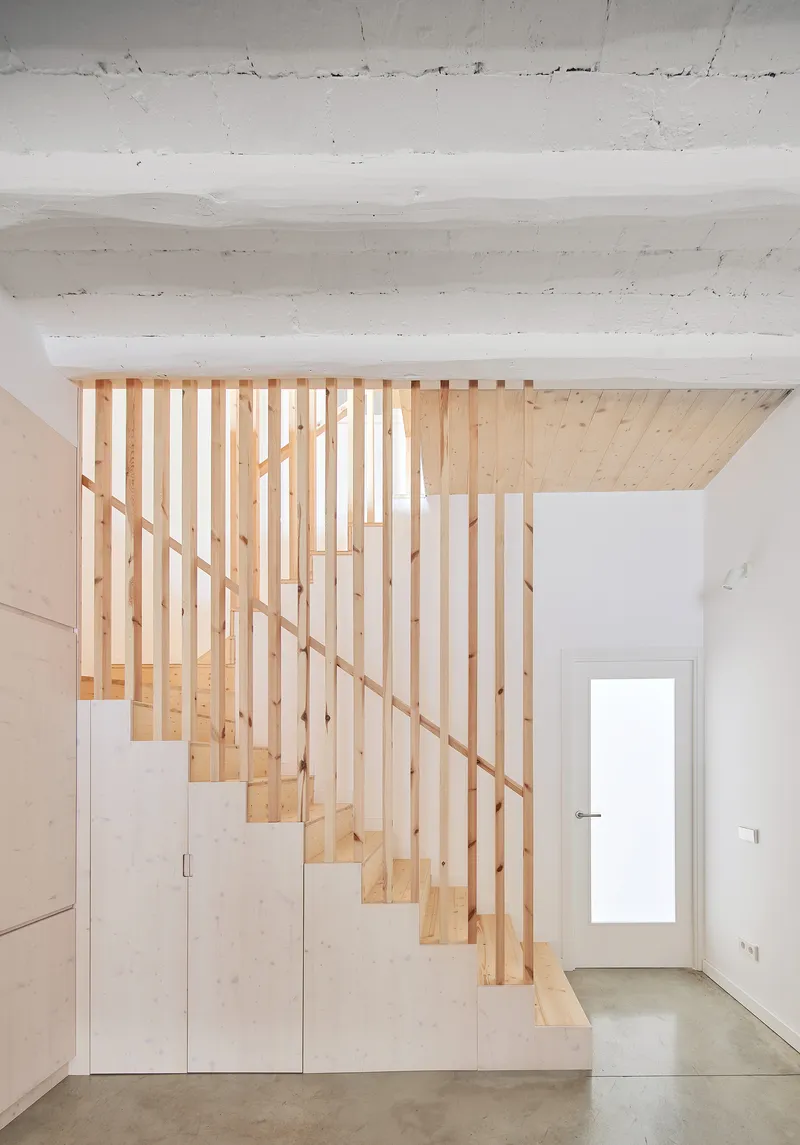 Timber staircase with vertical slat balustrade and plywood storage cabinets beneath the treads