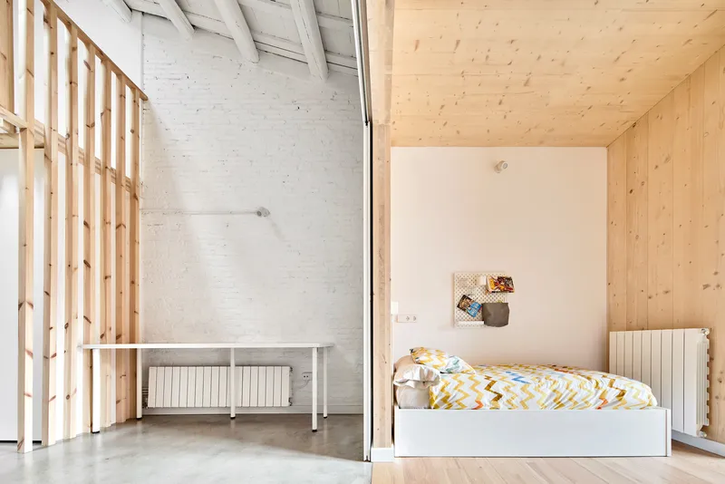 Sleeping alcove with single bed beside timber slat screen and polished concrete floor