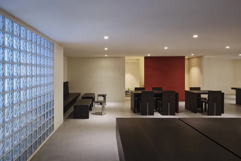 Seating area with black tables and chairs beside a textured glass block wall