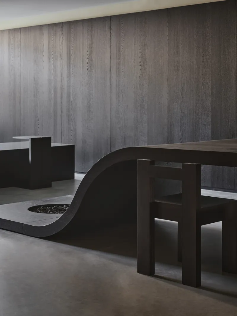 Sculptural black seating elements against a vertically ribbed concrete wall
