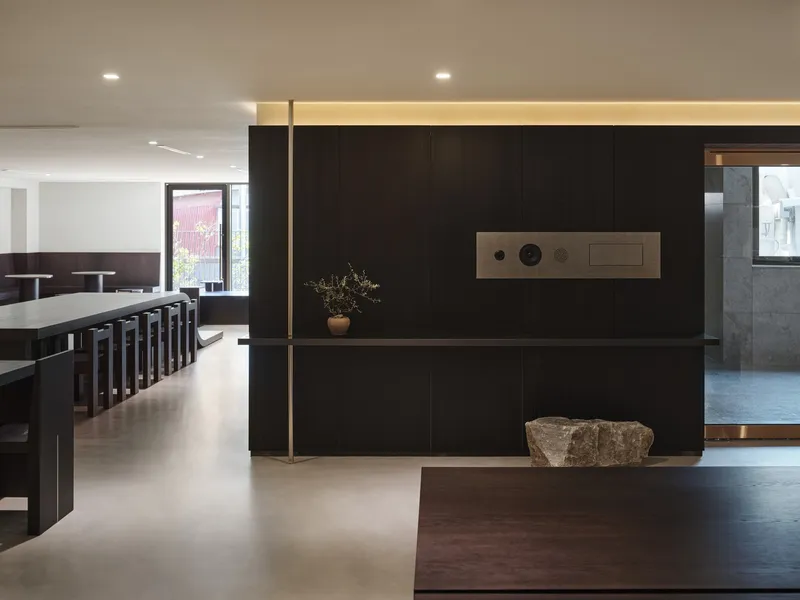 Black panel wall with integrated controls and a raw stone placed at its base