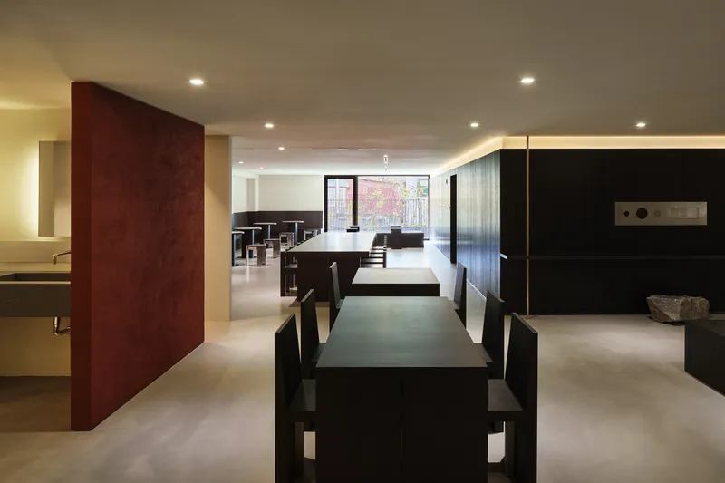 Long interior dining hall with rows of dark tables and red panel dividing the space