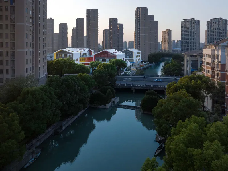 Distant view of the clustered white rooftops along a canal at dusk with highrise towers behind