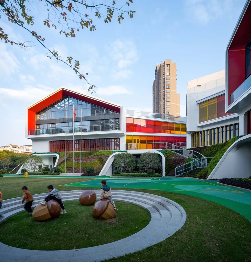 Outdoor play area with circular stepped seating and wooden climbing spheres beneath spring tree branches