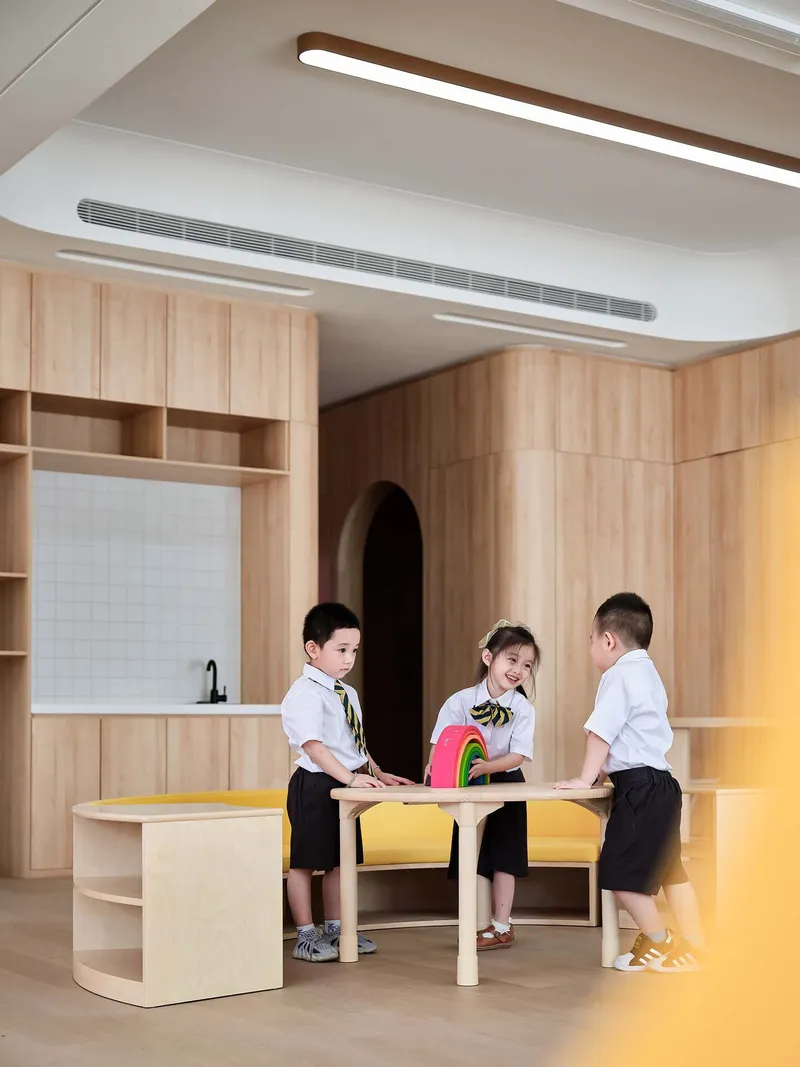 Light wood millwork classroom with white tile backsplash and children seated at a table