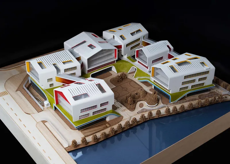Physical model of white barrel-vaulted buildings with colored accents arranged around a central green