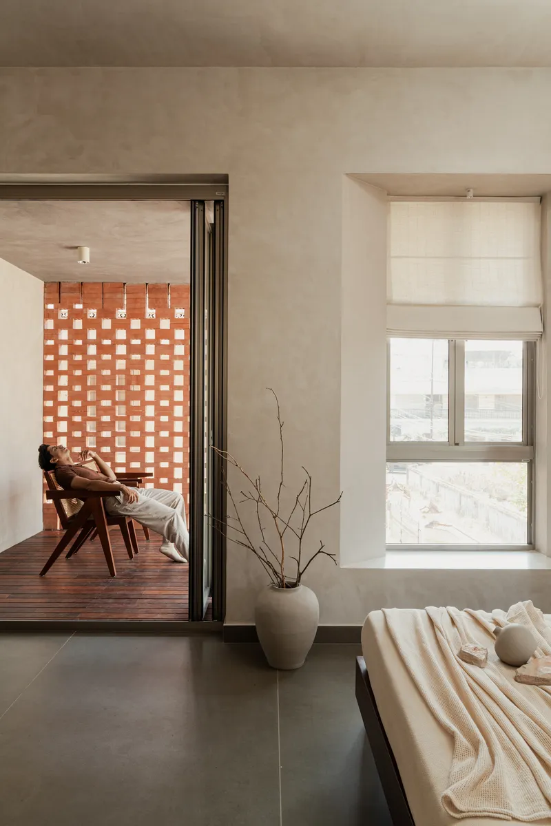 Bedroom with view through folding glass doors to timber deck and perforated brick screen beyond