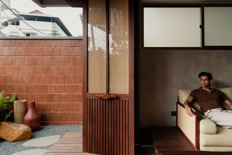 Interior lounge space with slatted timber partition opening to courtyard with terracotta tile wall