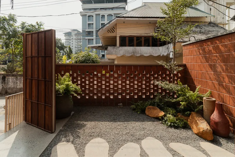 Courtyard garden with perforated terracotta screen wall and gravel flooring surrounded by timber cladding and planters