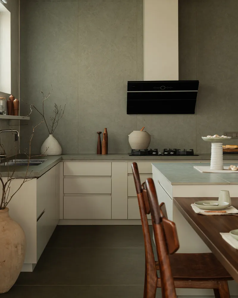 Kitchen corner with pale cabinetry and textured wall panels beneath a black range hood