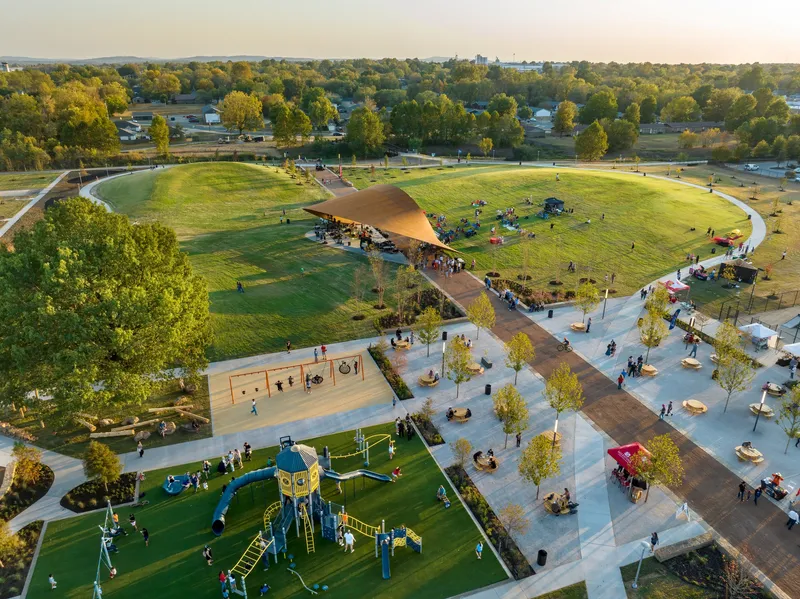 Drone view of the park showing the pavilion, playground, plaza and lawn at golden hour
