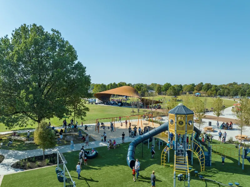 Aerial view of playground equipment and canopy pavilion in the park with families playing below