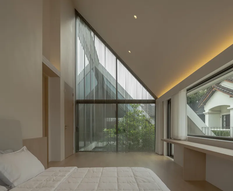 Bedroom with gabled glass wall framing bamboo grove and slatted screen beyond