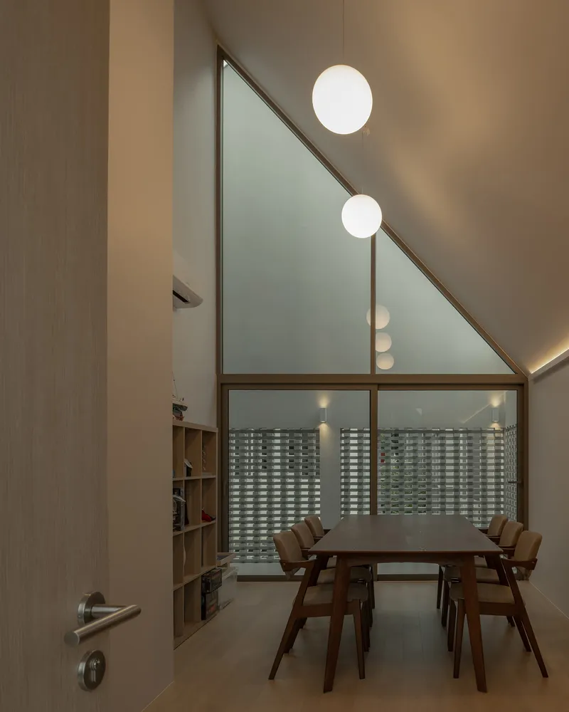 Dining room with angled ceiling featuring frosted glass gable window and spherical pendant lights at dusk